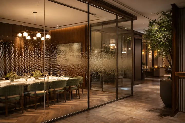 Ceramic dot-gradient glass partition screening a private restaurant dining area