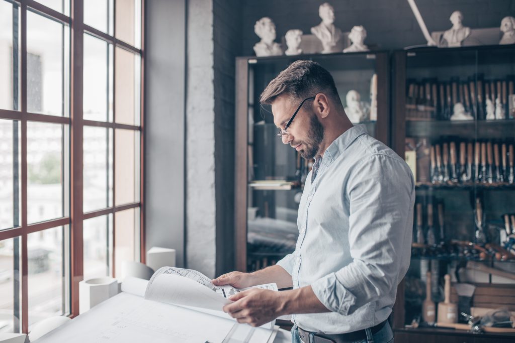 Architect reviewing building plans for a commercial glazing project