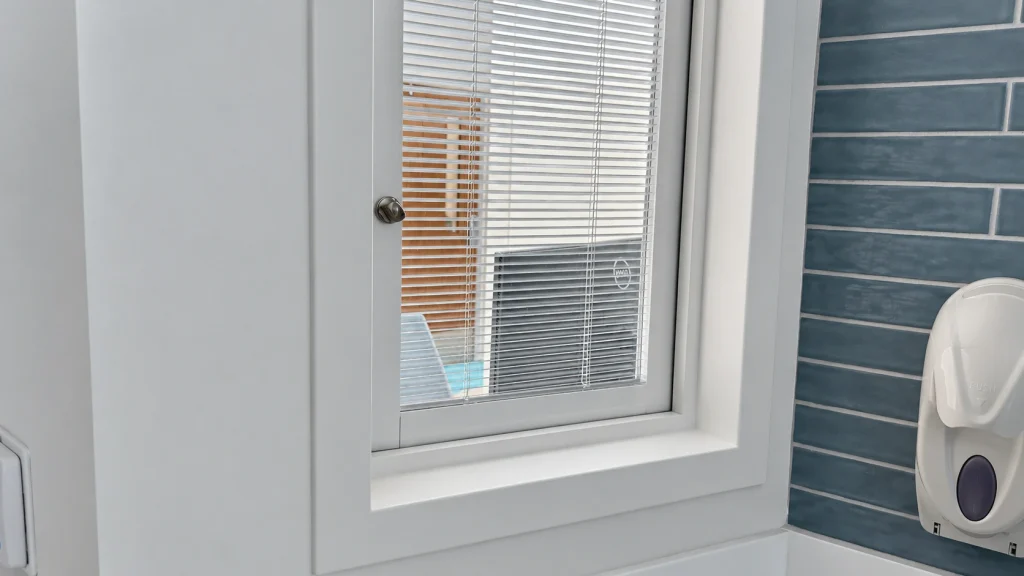 Interior window with enclosed Venetian blinds and an anti-ligature control knob at AdventHealth Daytona Beach.