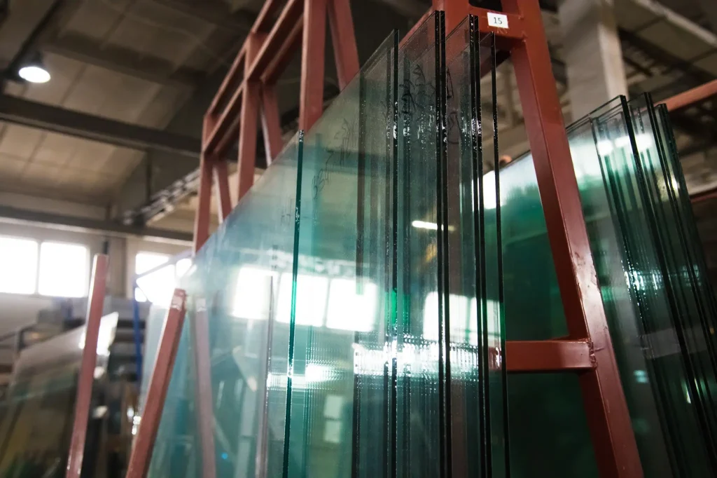 Multiple architectural glass panes stored on factory racks for commercial construction
